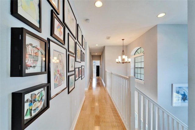 corridor with a notable chandelier and light hardwood / wood-style floors