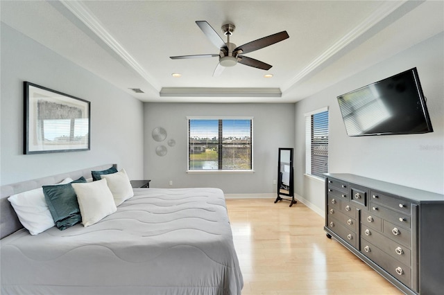 bedroom featuring a raised ceiling, ornamental molding, ceiling fan, and light hardwood / wood-style floors