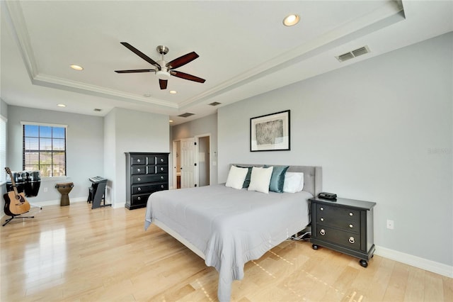 bedroom with ornamental molding, ceiling fan, light hardwood / wood-style floors, and a tray ceiling