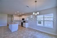 kitchen with a center island, decorative light fixtures, range, a notable chandelier, and white cabinetry