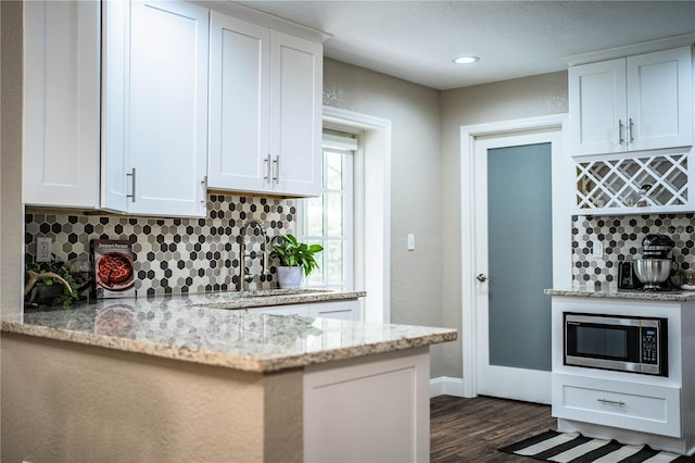 kitchen featuring stainless steel microwave, white cabinets, dark hardwood / wood-style flooring, and light stone counters