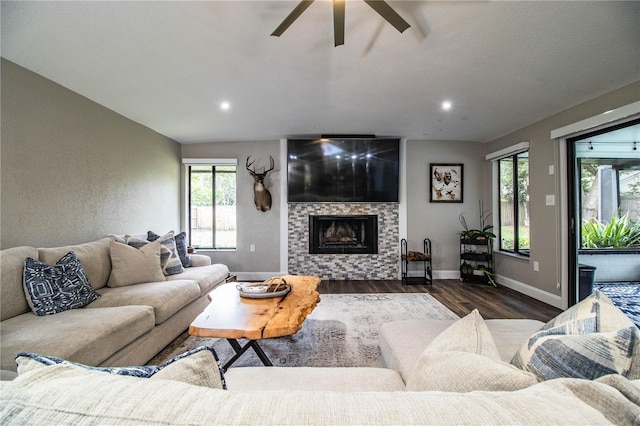 living room with ceiling fan, dark hardwood / wood-style flooring, and a tiled fireplace