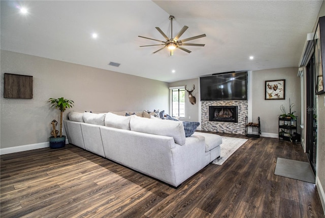 living room with dark wood-type flooring, a tiled fireplace, and ceiling fan