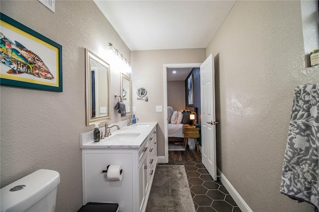 bathroom with toilet, vanity, and tile patterned flooring