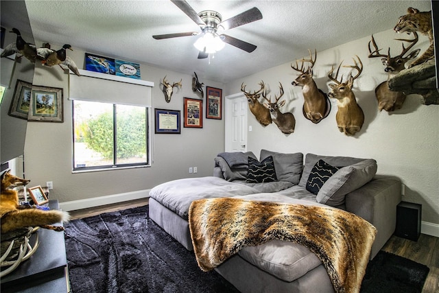 bedroom with ceiling fan, a textured ceiling, and dark hardwood / wood-style floors