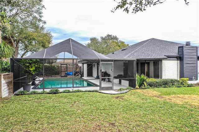 rear view of property featuring glass enclosure, a lawn, and a patio