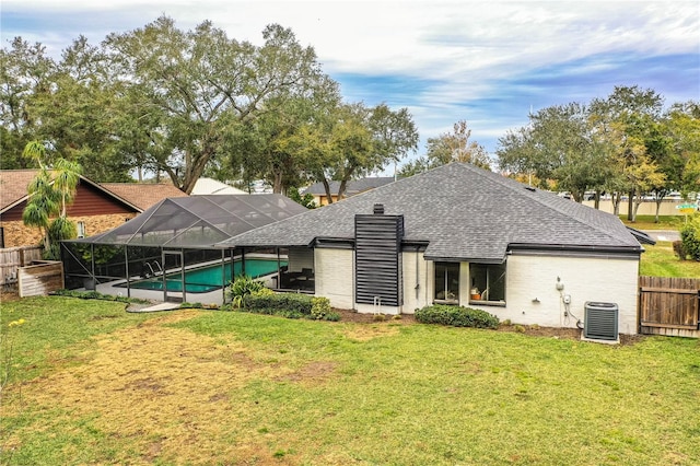 back of house featuring a lanai, central AC, a lawn, and a fenced in pool