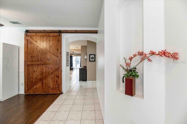 corridor with light tile patterned flooring and a barn door