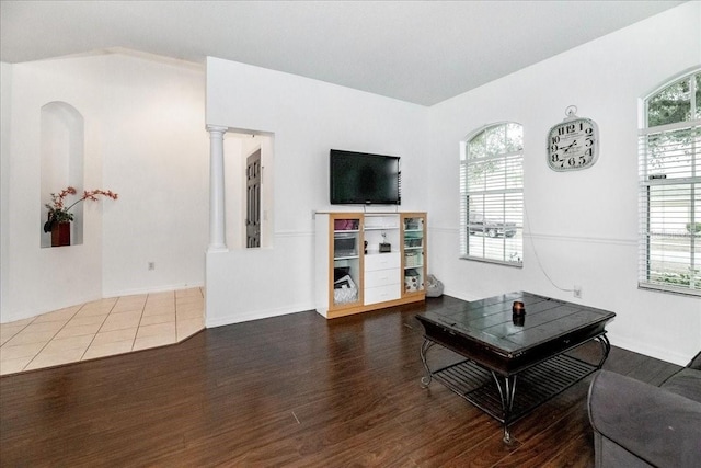 living room featuring wood-type flooring, ornate columns, and vaulted ceiling