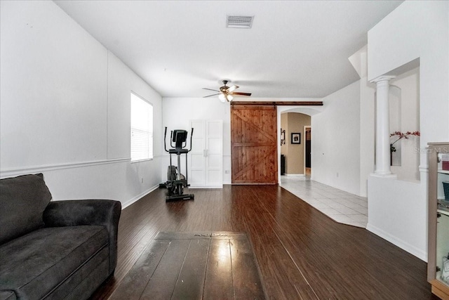 living room with ceiling fan, dark hardwood / wood-style flooring, and ornate columns