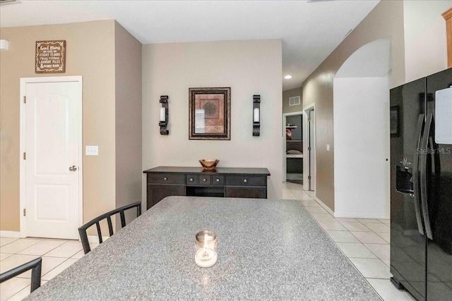 kitchen featuring black fridge with ice dispenser and light tile patterned floors