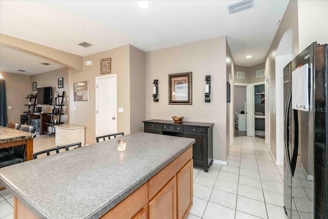 kitchen featuring black fridge, light tile patterned floors, and a kitchen island