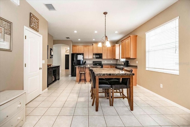 kitchen with decorative light fixtures, black appliances, sink, light tile patterned flooring, and light brown cabinets