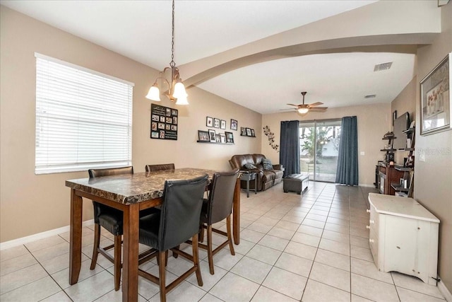 tiled dining room with ceiling fan with notable chandelier