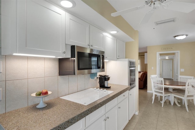 kitchen featuring ceiling fan, white cabinetry, light tile patterned floors, decorative backsplash, and stainless steel appliances