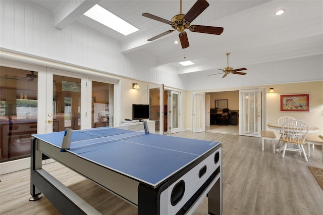 recreation room with light wood-type flooring, ceiling fan, french doors, and lofted ceiling with skylight