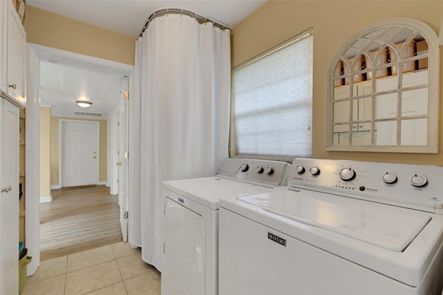 clothes washing area with washing machine and clothes dryer and light tile patterned floors