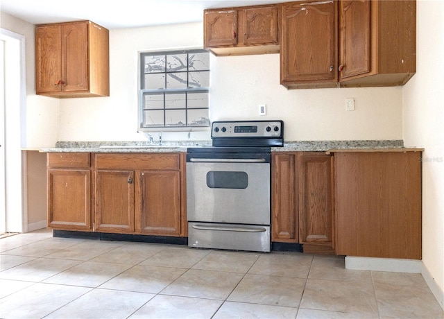 kitchen featuring light stone countertops, electric range, light tile patterned floors, and sink