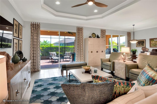 living room with a raised ceiling, ceiling fan, and crown molding