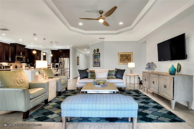 living room featuring ceiling fan, ornamental molding, and a raised ceiling