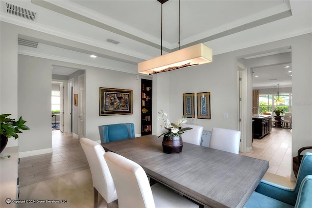 dining space with a tray ceiling and ornamental molding