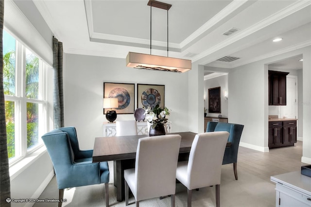 dining room featuring crown molding, a raised ceiling, and light hardwood / wood-style flooring