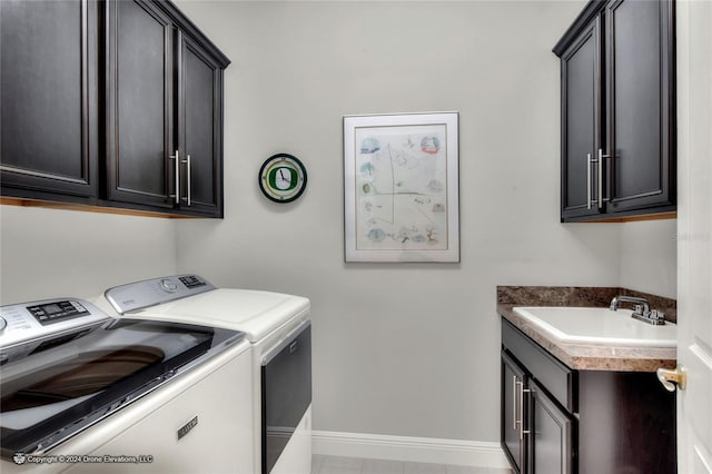 clothes washing area featuring cabinets, sink, and washing machine and clothes dryer