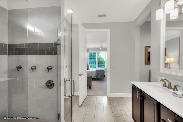 bathroom featuring a shower with shower door and vanity