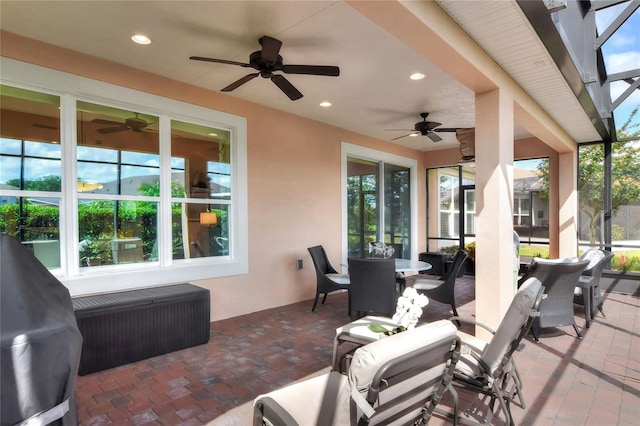 view of patio featuring ceiling fan, a grill, and glass enclosure