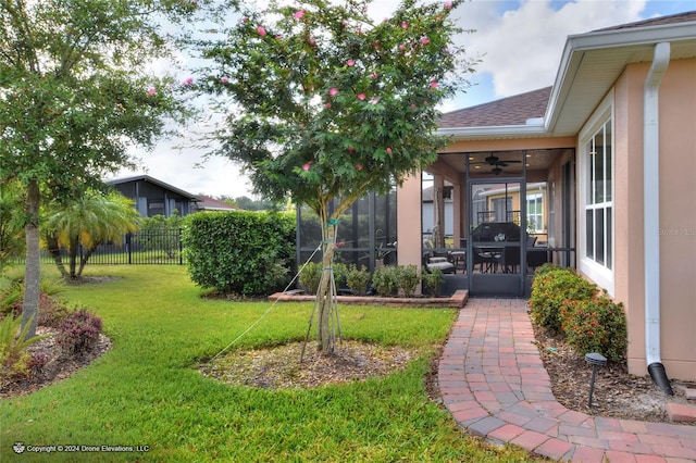 view of yard featuring ceiling fan and a sunroom