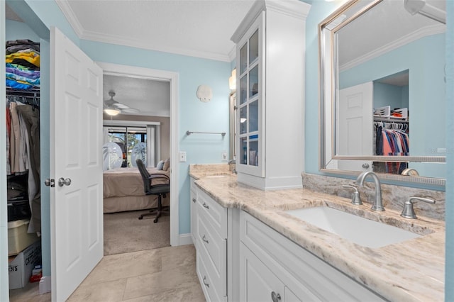 bathroom with a textured ceiling, ceiling fan, crown molding, and vanity