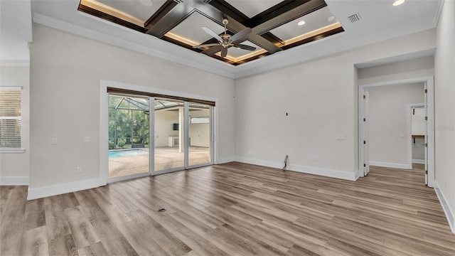 empty room with ceiling fan, a high ceiling, coffered ceiling, ornamental molding, and light wood-type flooring