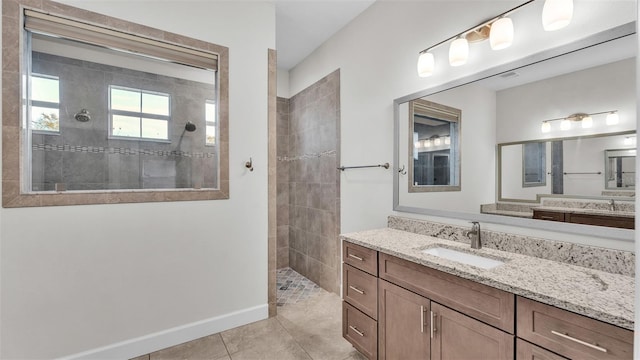 bathroom with tile patterned flooring, vanity, and tiled shower