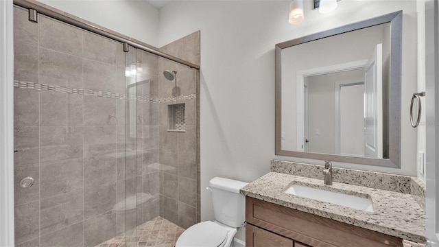 bathroom featuring vanity, a shower with shower door, and toilet