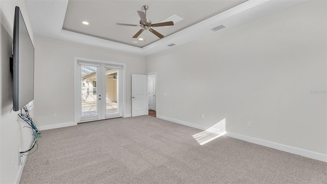 empty room featuring a raised ceiling, light carpet, ceiling fan, and french doors