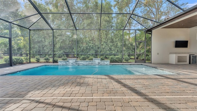 view of pool with pool water feature, an outdoor kitchen, glass enclosure, and a patio area