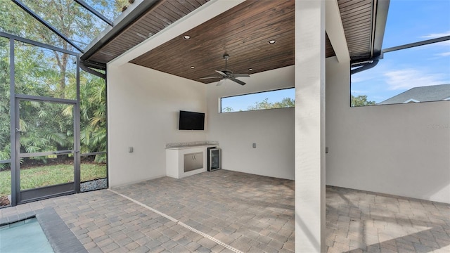 view of patio featuring glass enclosure, ceiling fan, and exterior kitchen