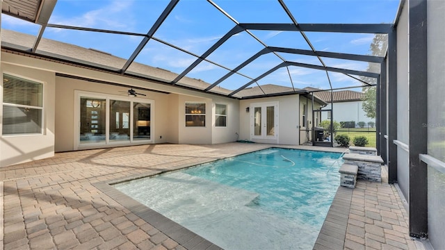 view of swimming pool featuring a patio, pool water feature, ceiling fan, and glass enclosure