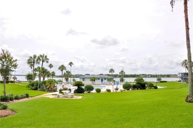 surrounding community featuring a water view, a pool, and a lawn