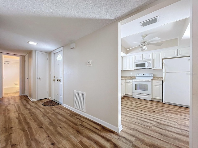 hall featuring light wood-type flooring and a textured ceiling