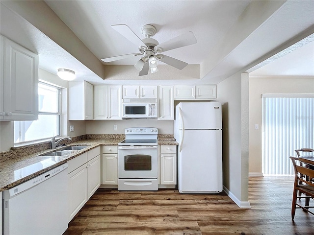 kitchen with white appliances, white cabinets, sink, hardwood / wood-style flooring, and stone counters