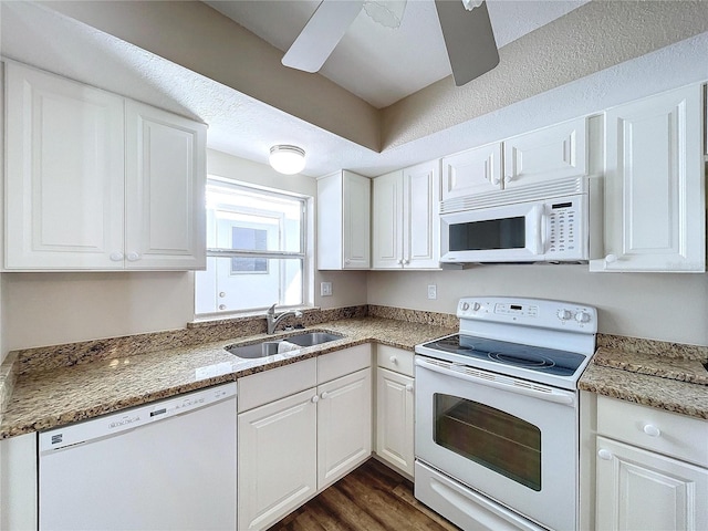 kitchen featuring white appliances, white cabinetry, dark hardwood / wood-style flooring, dark stone countertops, and sink