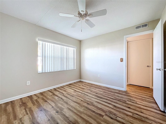 empty room with ceiling fan, hardwood / wood-style floors, and a textured ceiling