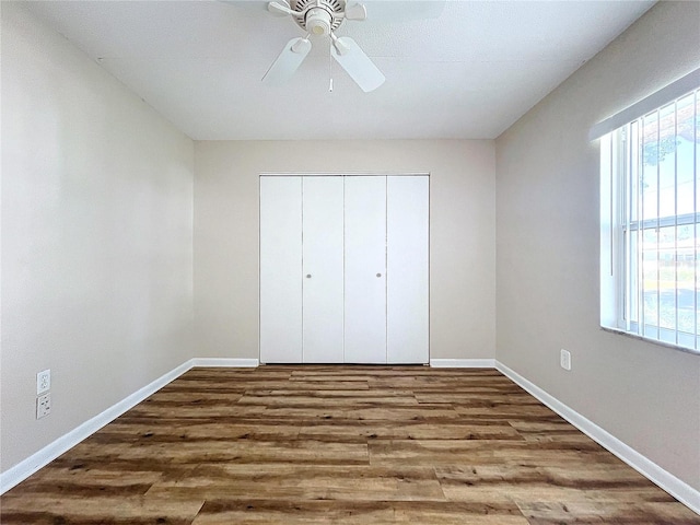 unfurnished bedroom featuring ceiling fan, a closet, and wood-type flooring