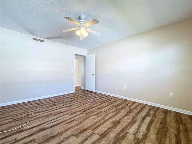 empty room with ceiling fan, a textured ceiling, and hardwood / wood-style flooring