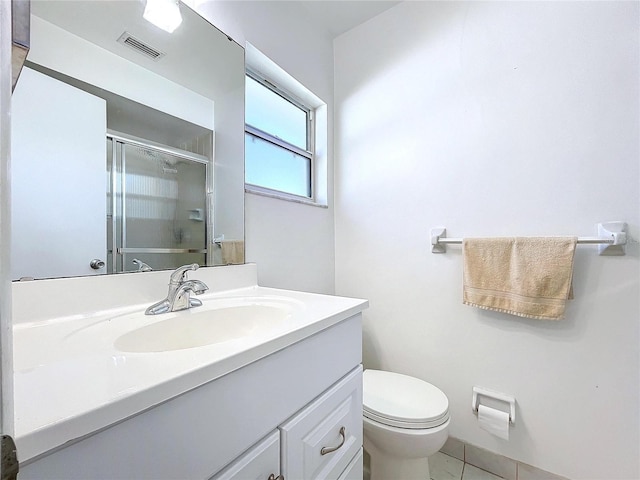 bathroom featuring a shower with shower door, vanity, tile patterned flooring, and toilet