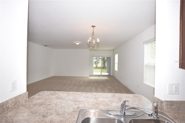 kitchen with light colored carpet, hanging light fixtures, sink, and an inviting chandelier