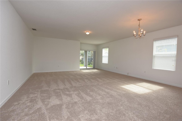 spare room with an inviting chandelier and light colored carpet