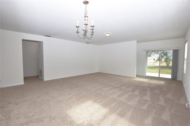 carpeted empty room with a notable chandelier