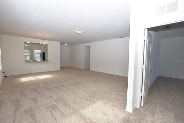 unfurnished living room featuring light carpet and a notable chandelier